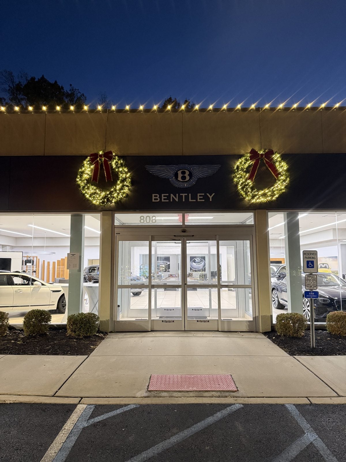 A Bentley showroom entrance with lit wreaths flanking the doors