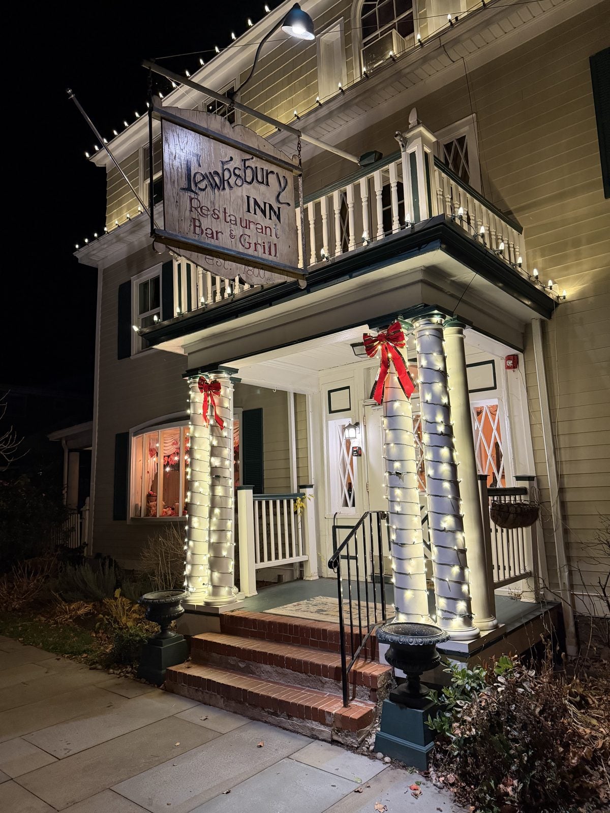 An inn entrance dressed with lit garland and red bows on the columns and railings