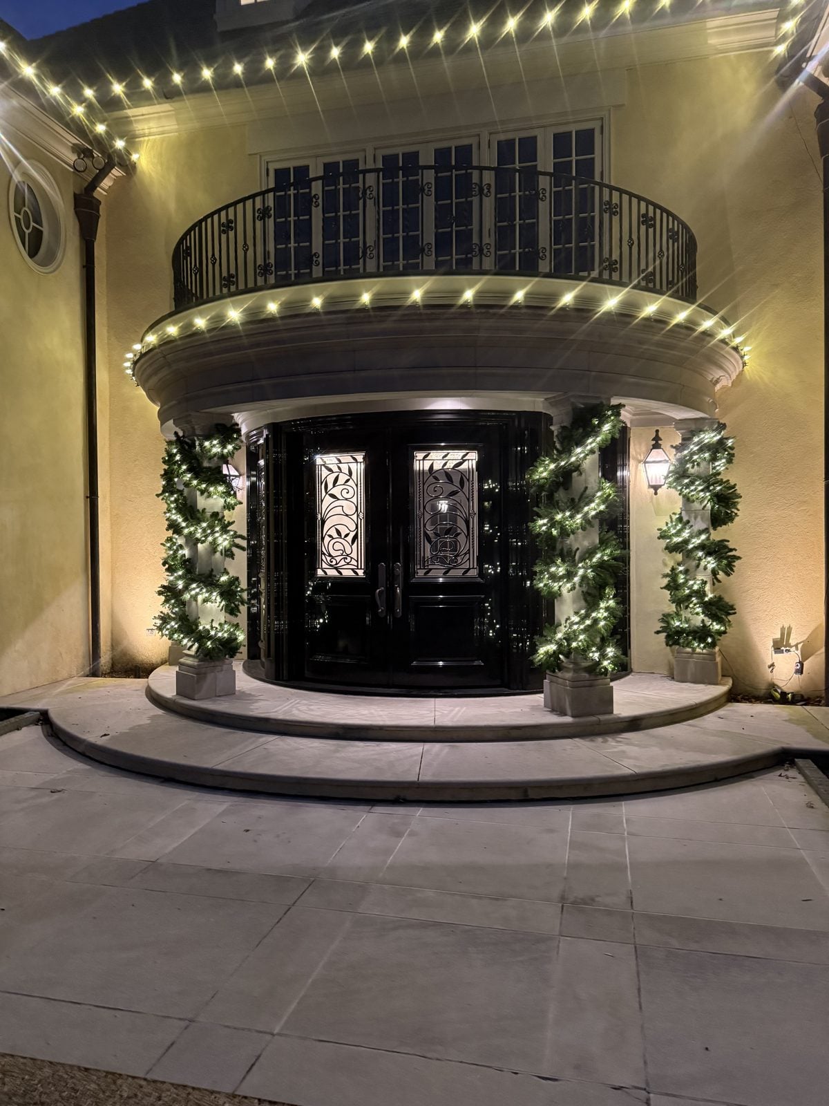 A curved commercial entrance with decorated evergreens either side of the doors