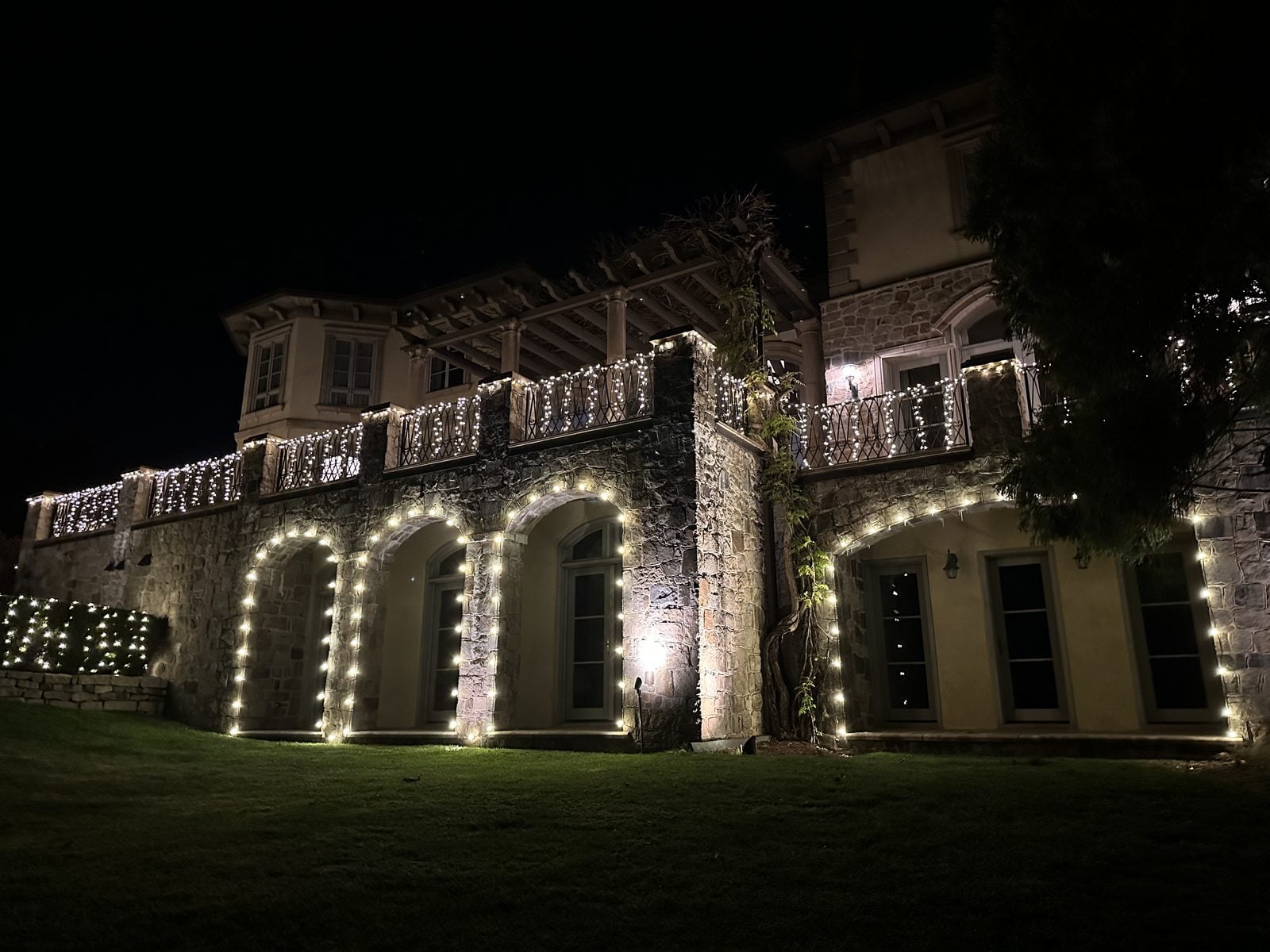 Stone arches wrapped in lights along a covered walk