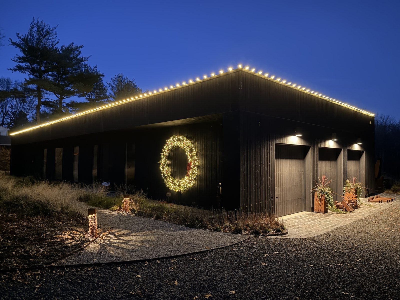 A long low building with a warm-lit roofline and an oversized wreath on the gable