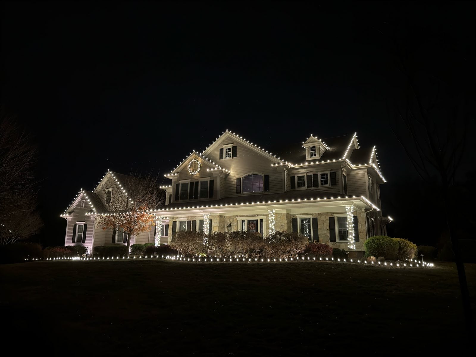 A house at blue hour with warm bulbs along every roofline