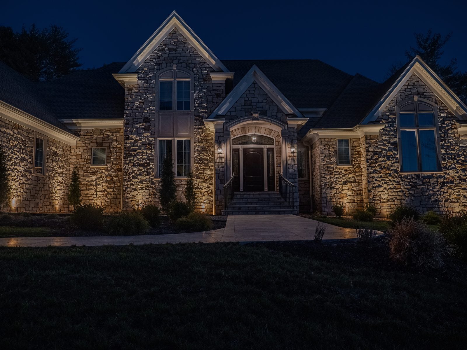 A stone-fronted home with each gable and stone face grazed from below