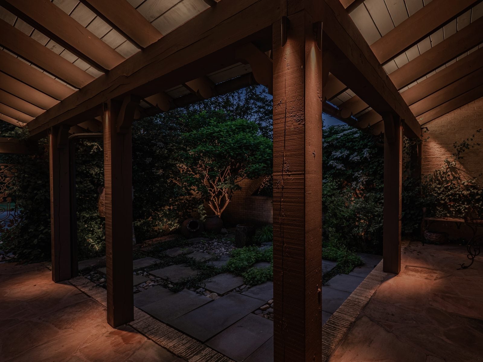 A patio lit after dark, the surrounding beds and structure brought up in light