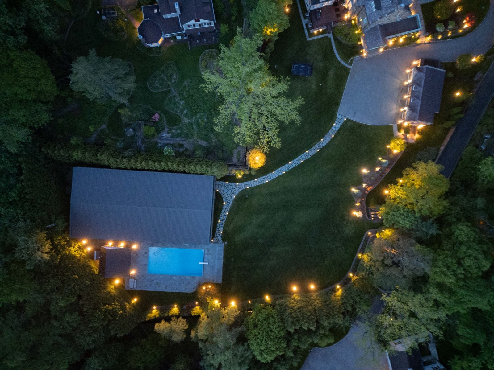 A lit estate seen from above after dark, the lighting scheme readable as one design