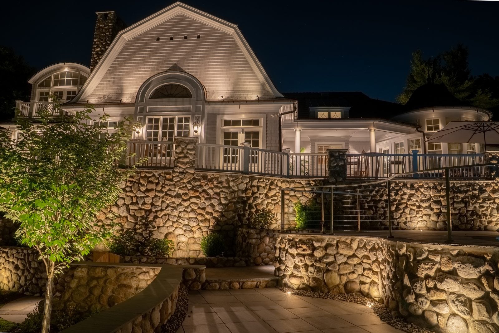 A lit home elevation at blue hour, planting beds washed from below