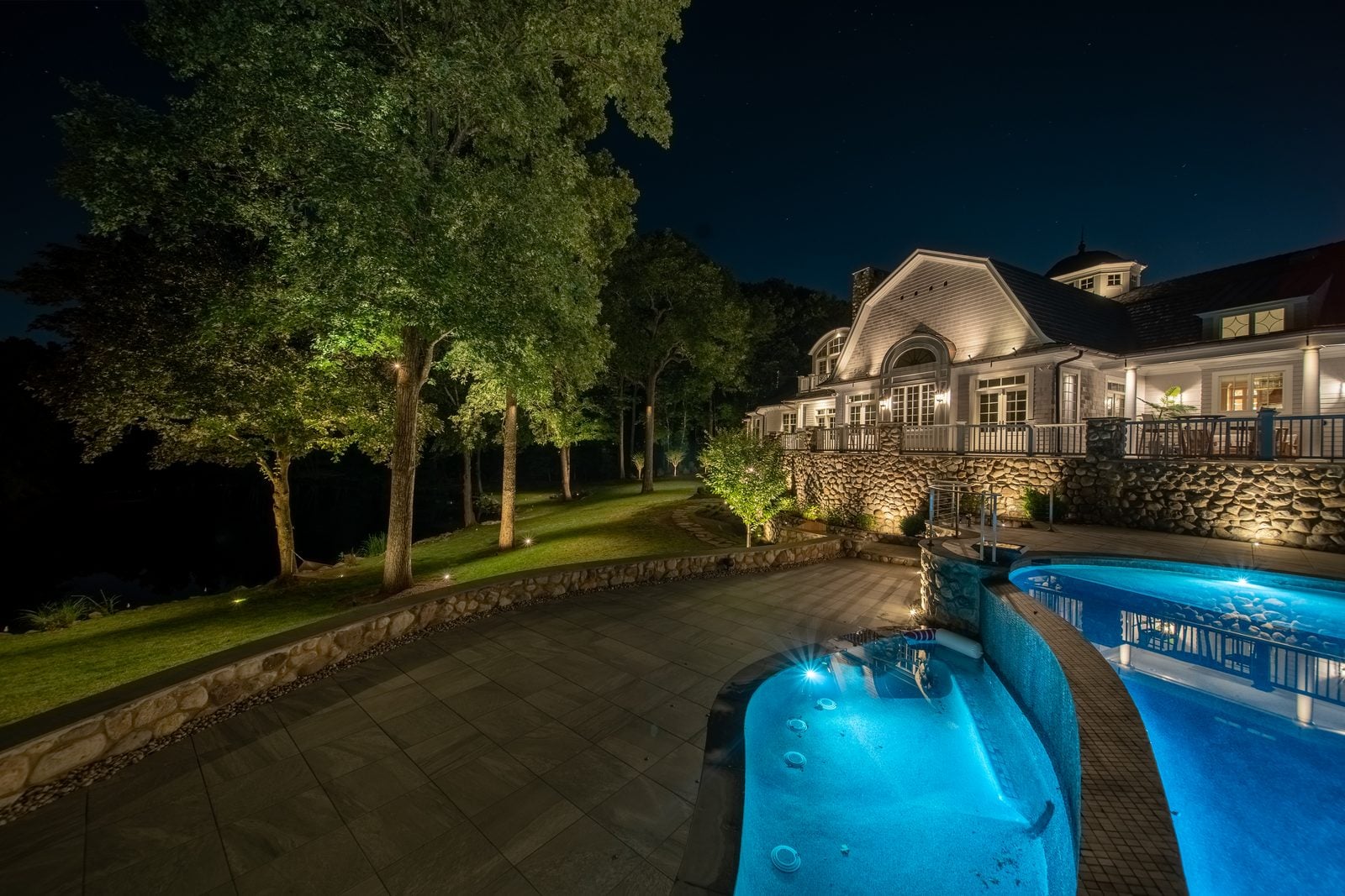 A pool lit from within, its stone surround washed warm