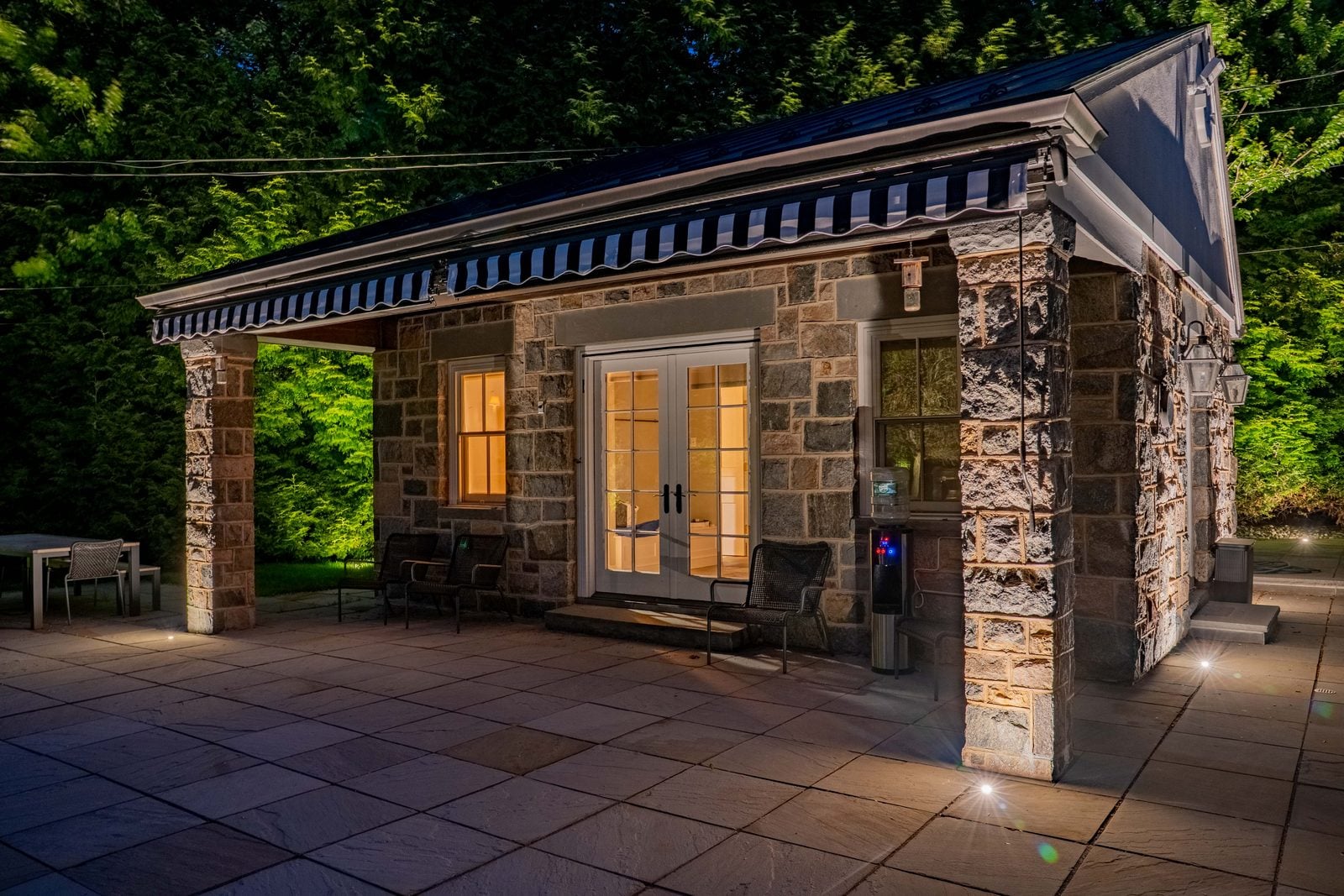 A lit patio and seating area, planting washed behind the furniture