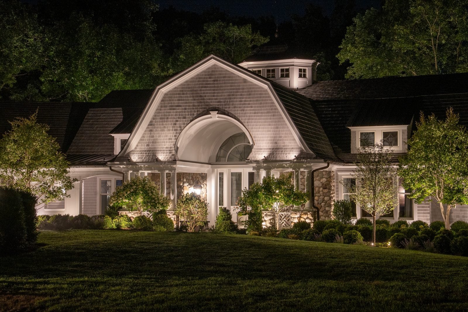 An entry and facade lit from the ground, the drive reading clearly up to the door