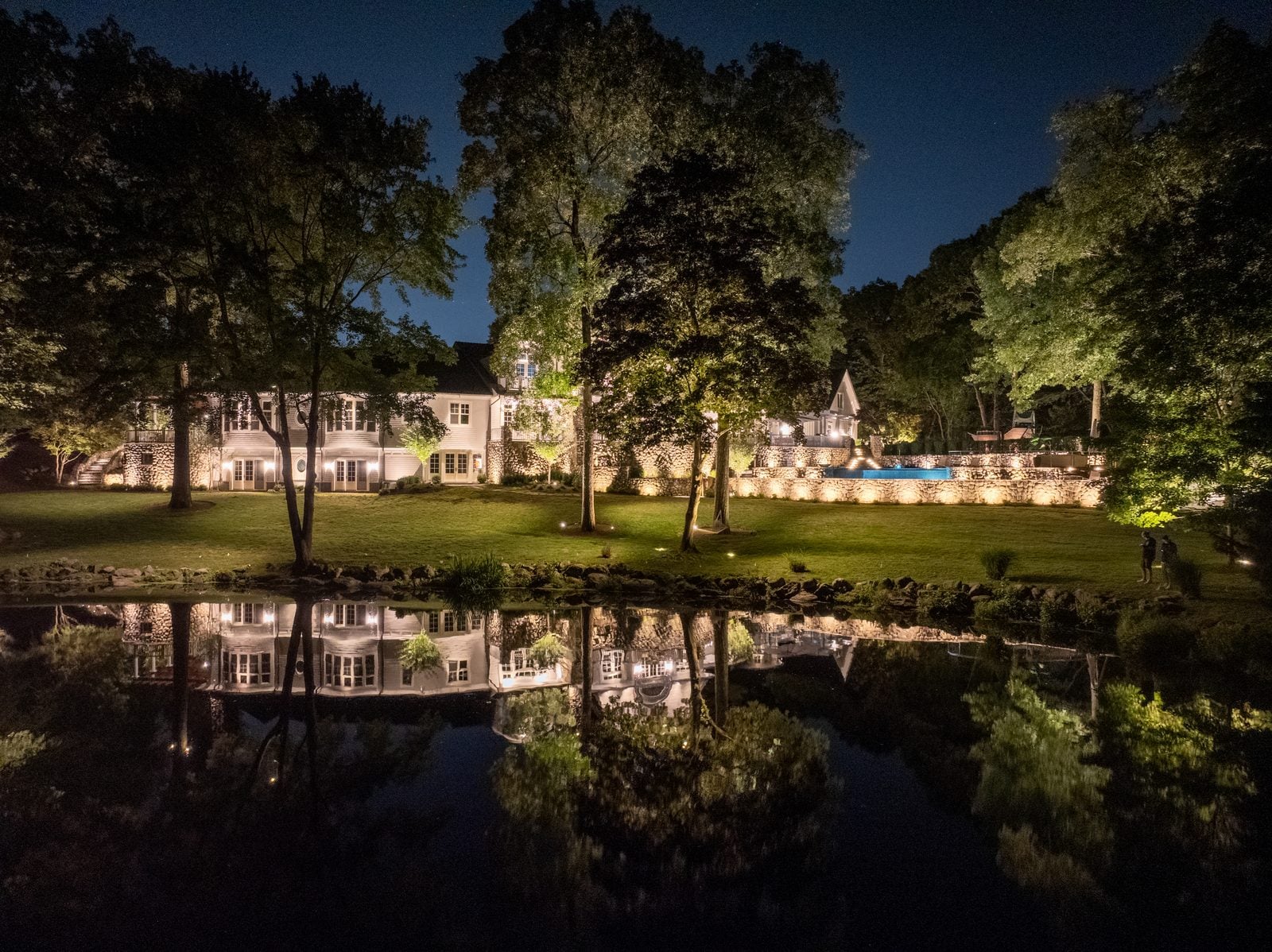 Still water at blue hour reflecting the uplit trees along its edge