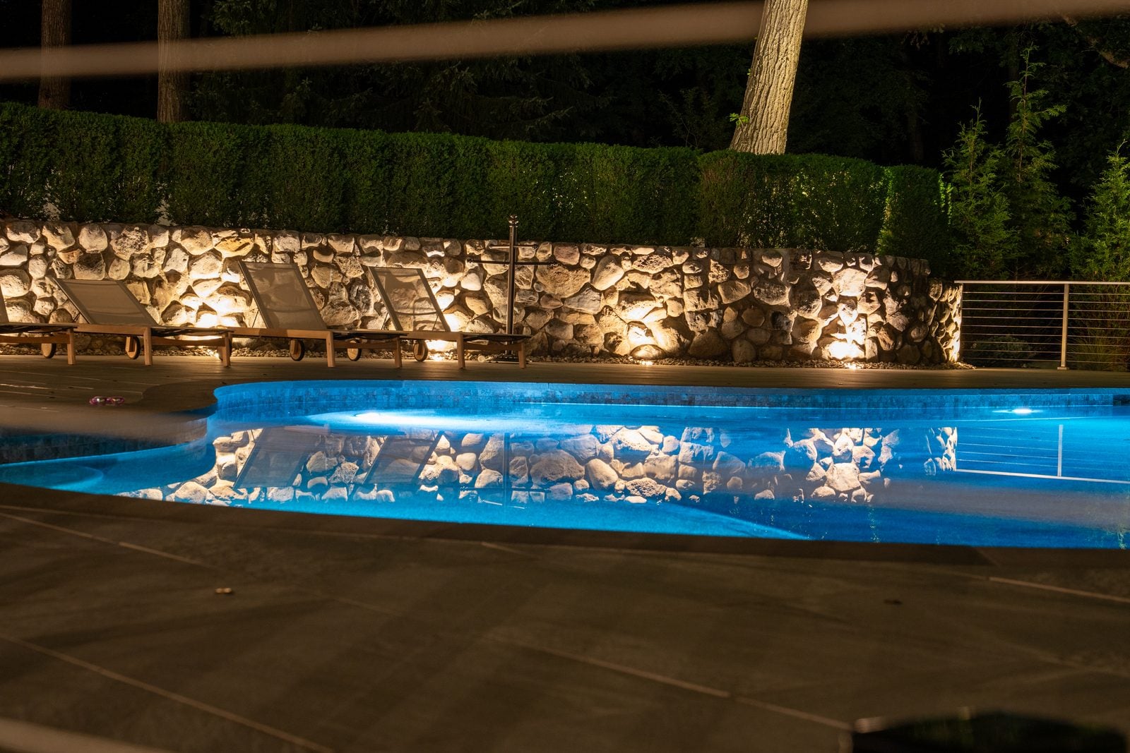 A pool lit from within, its stone surround washed warm