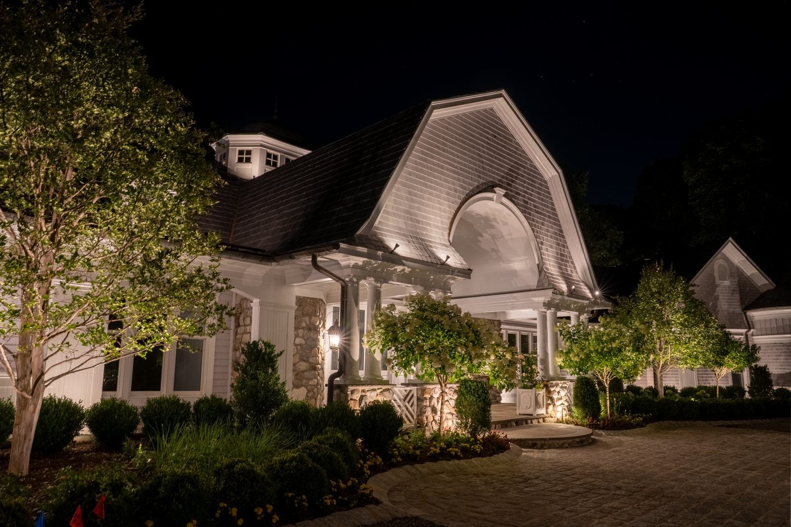 An entry and facade lit from the ground, the drive reading clearly up to the door