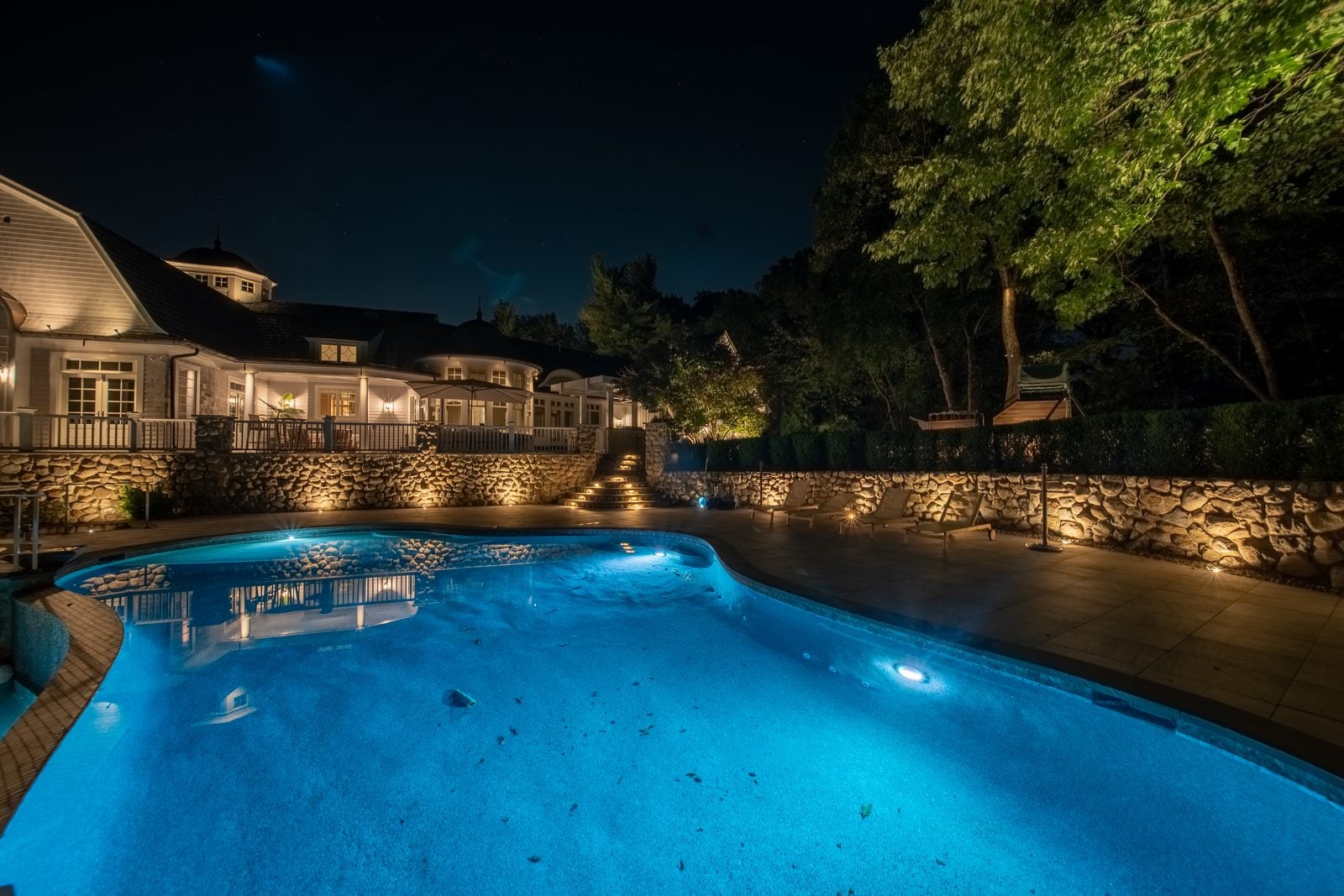 A garden pond lit at night, light doubled in the reflection