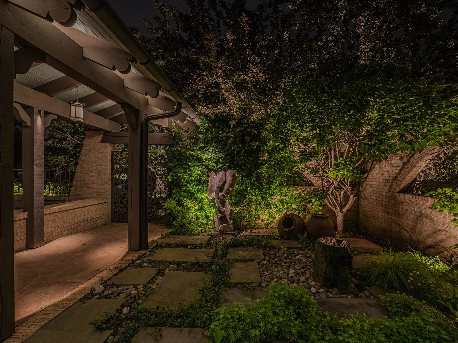 A garden path lit past dense planting at night