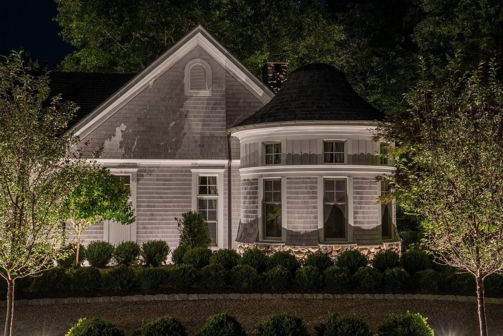 A house front lit after dark, the roofline and entry picked out against the night