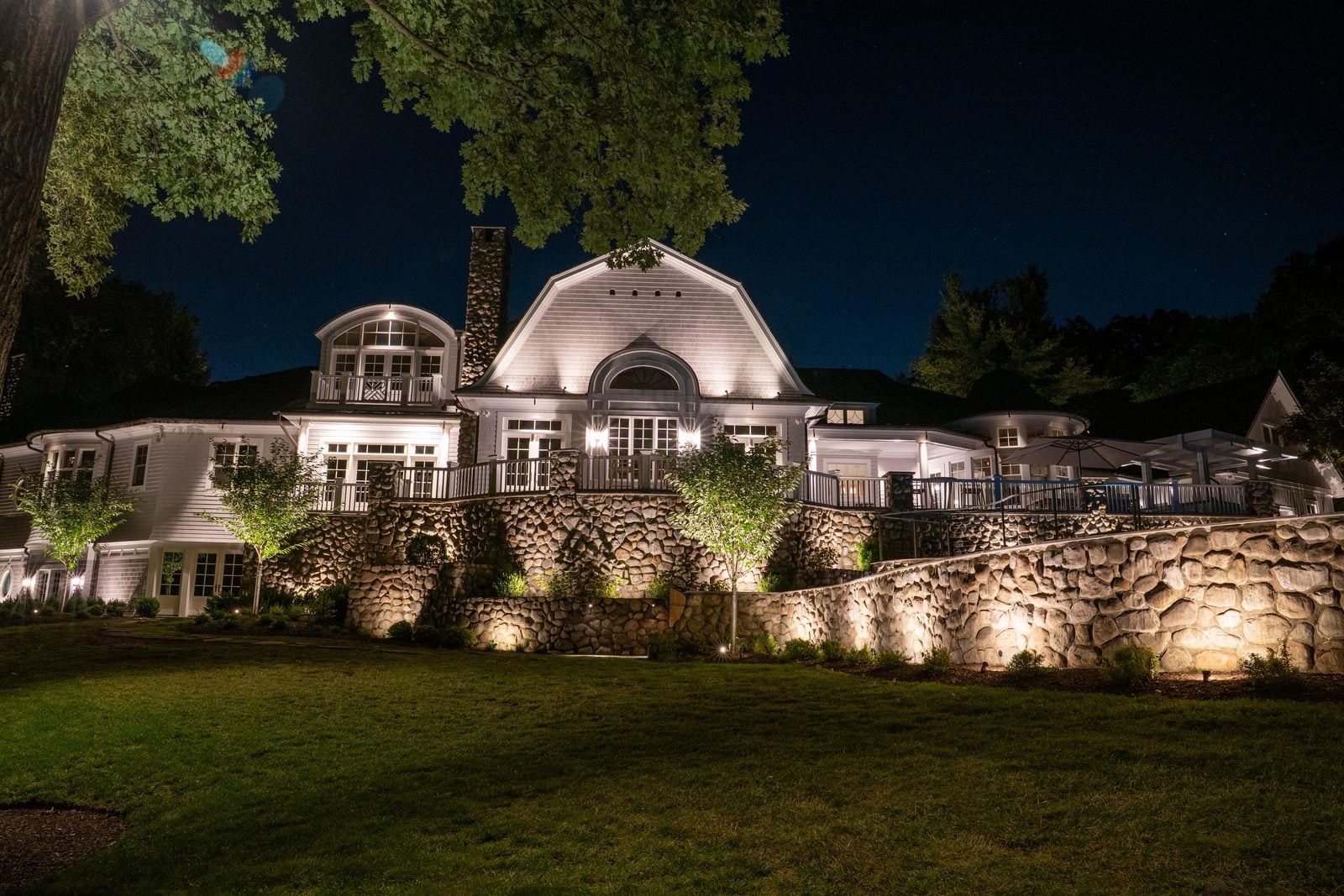 A lit home elevation at blue hour, planting beds washed from below