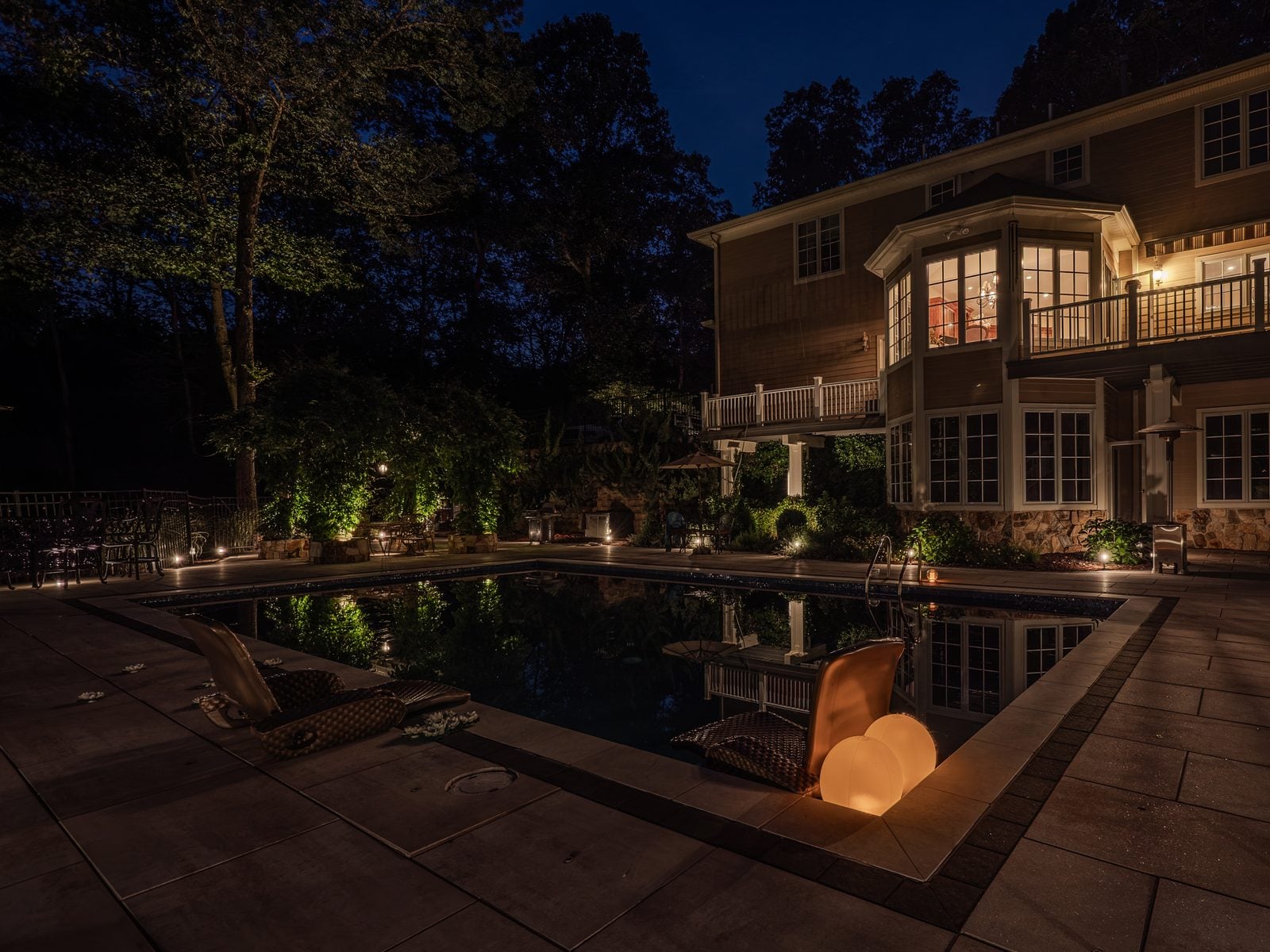 A pool lit from within, its stone surround washed warm