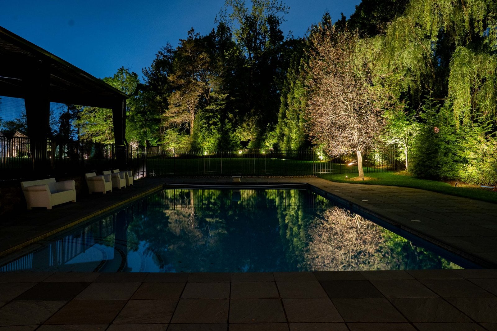 A garden pond lit at night, light doubled in the reflection