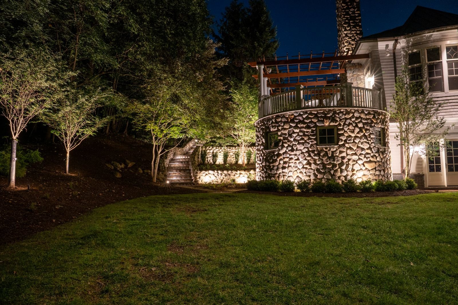 A New Jersey home at night with its facade washed in warm light from ground-set fixtures