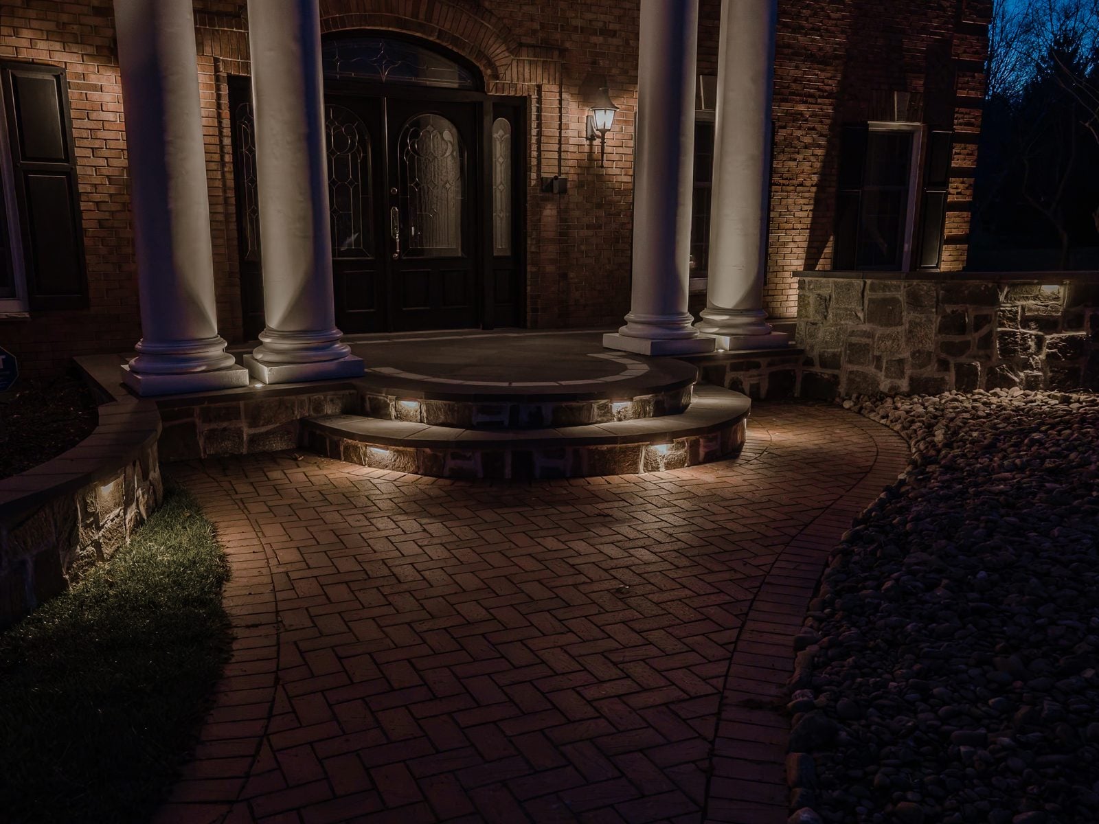 A house front lit after dark, the roofline and entry picked out against the night