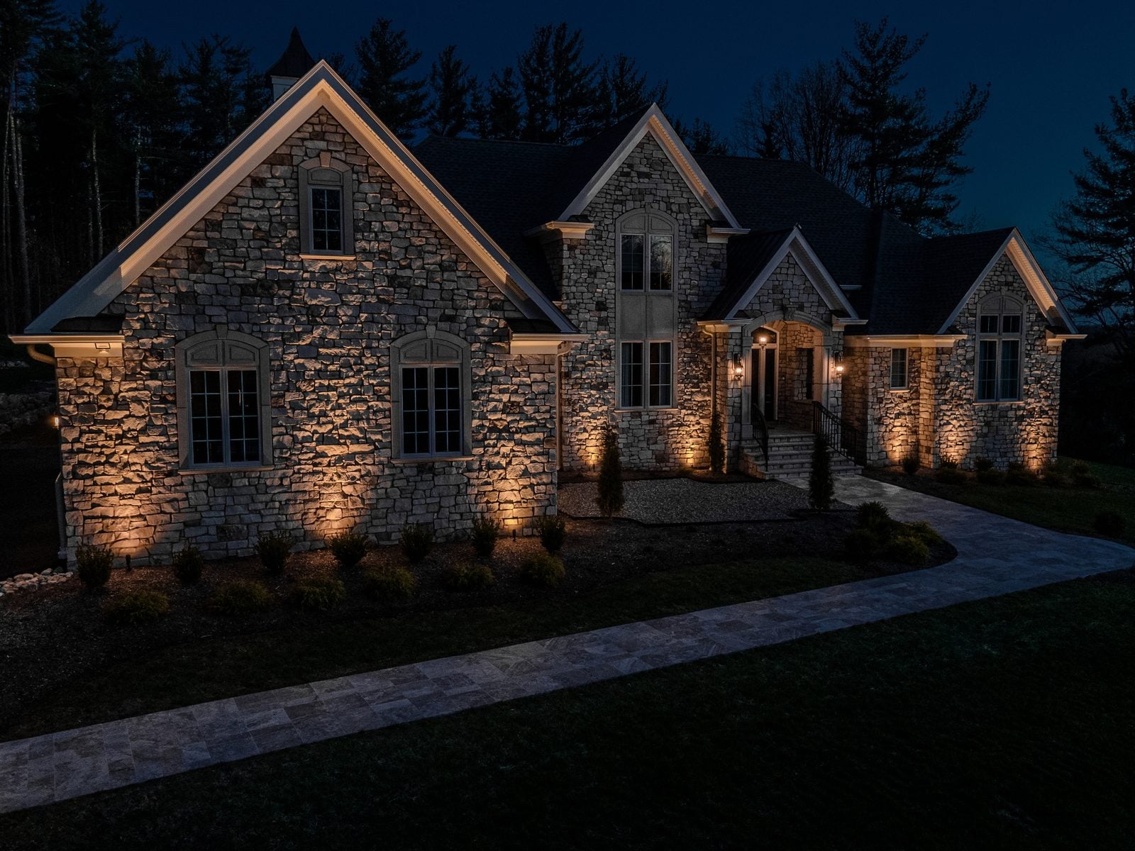 Warm light grazing the front of a home, gables and stonework brought forward