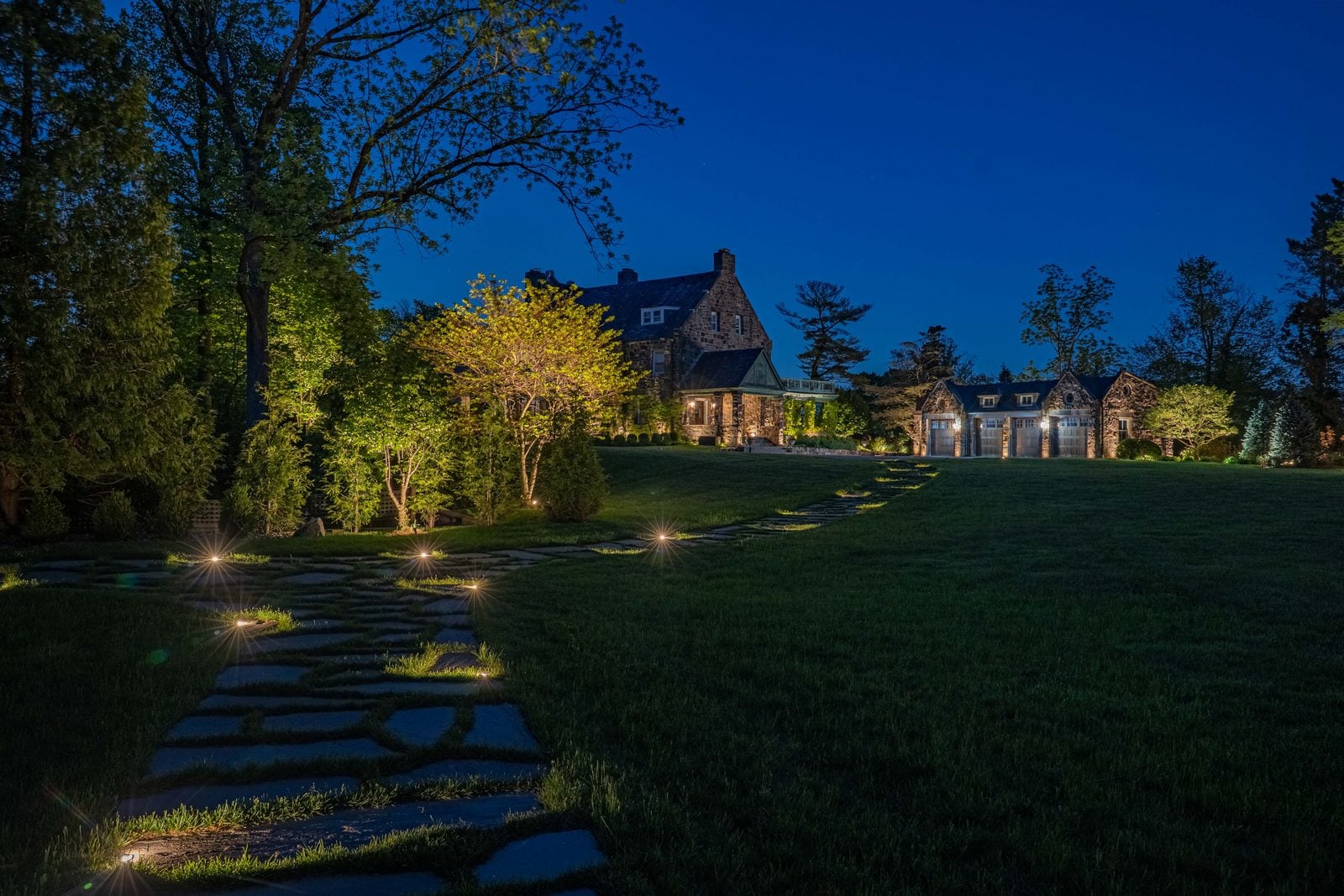 A pool lit from within, its stone surround washed warm