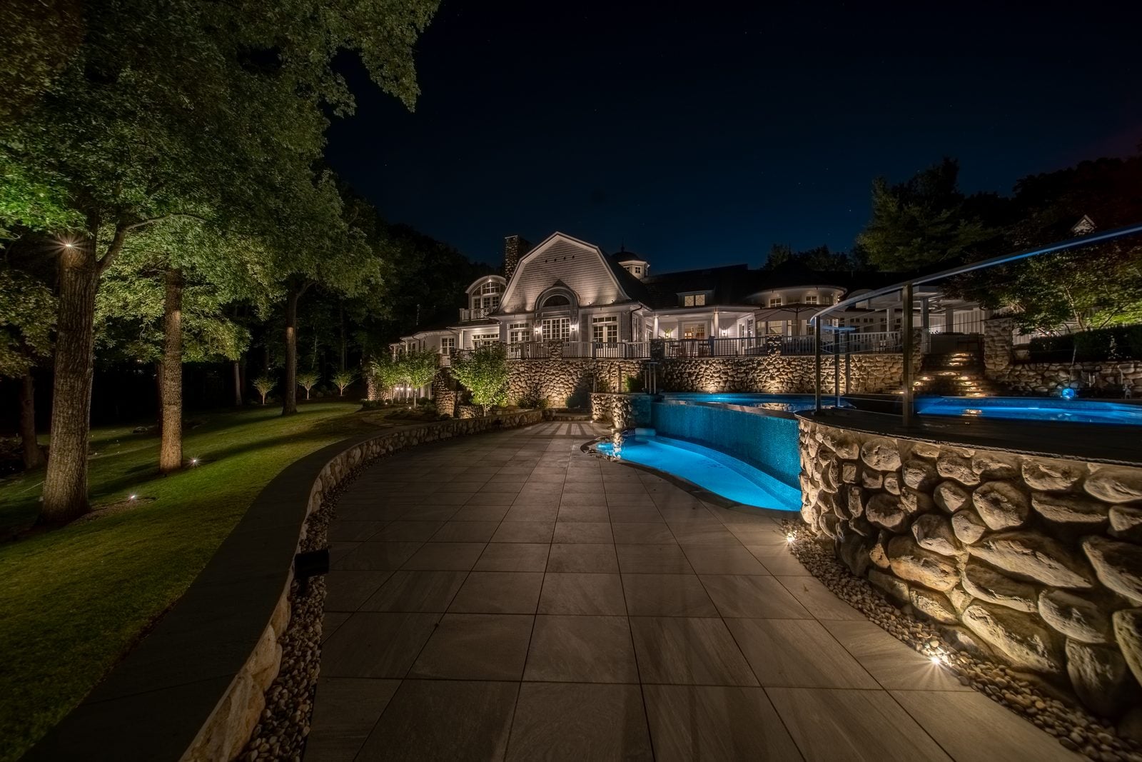 A garden pond lit at night, light doubled in the reflection