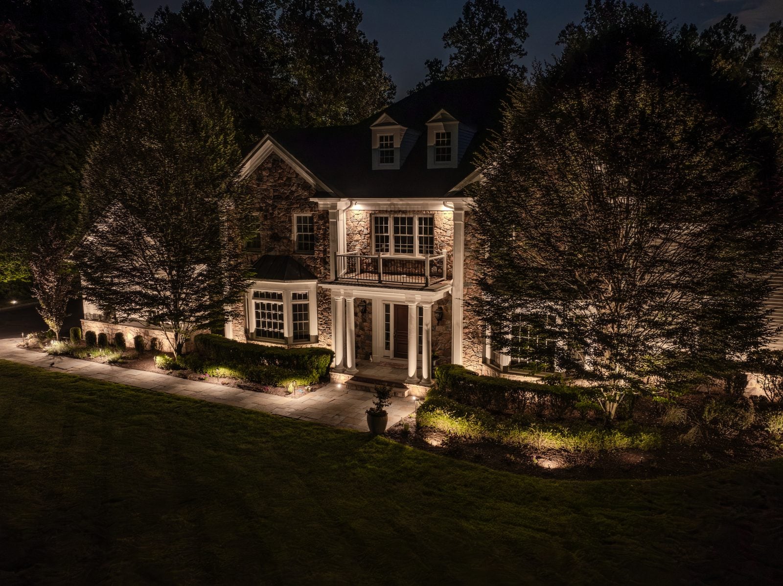 A house front lit after dark, the roofline and entry picked out against the night