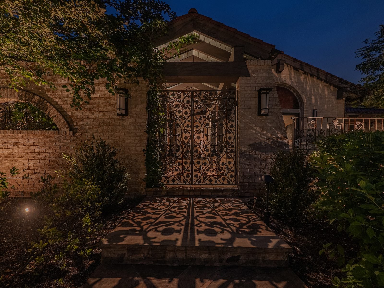 An entry and facade lit from the ground, the drive reading clearly up to the door