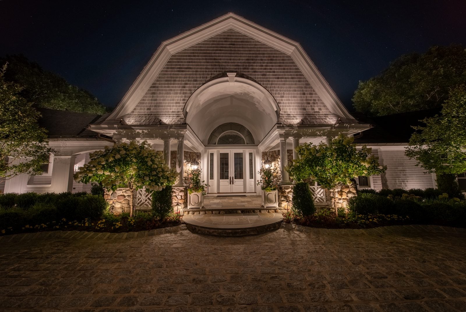 The arched entry of a shingled house, warm light raking across the shingles