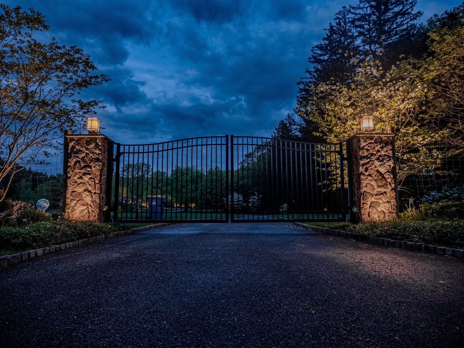 A lit home elevation at blue hour, planting beds washed from below