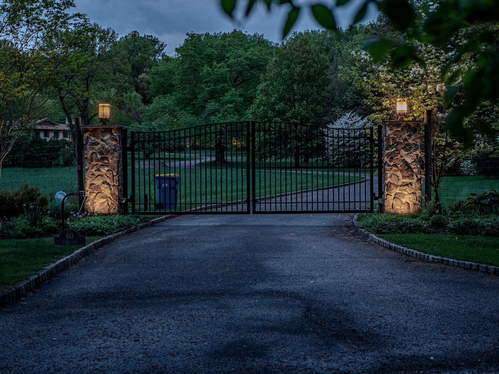 An entry and facade lit from the ground, the drive reading clearly up to the door