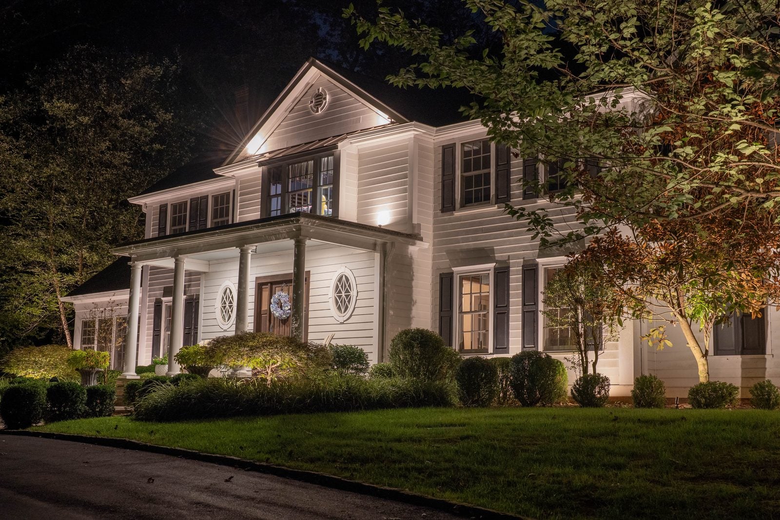 A New Jersey home at night with its facade washed in warm light from ground-set fixtures