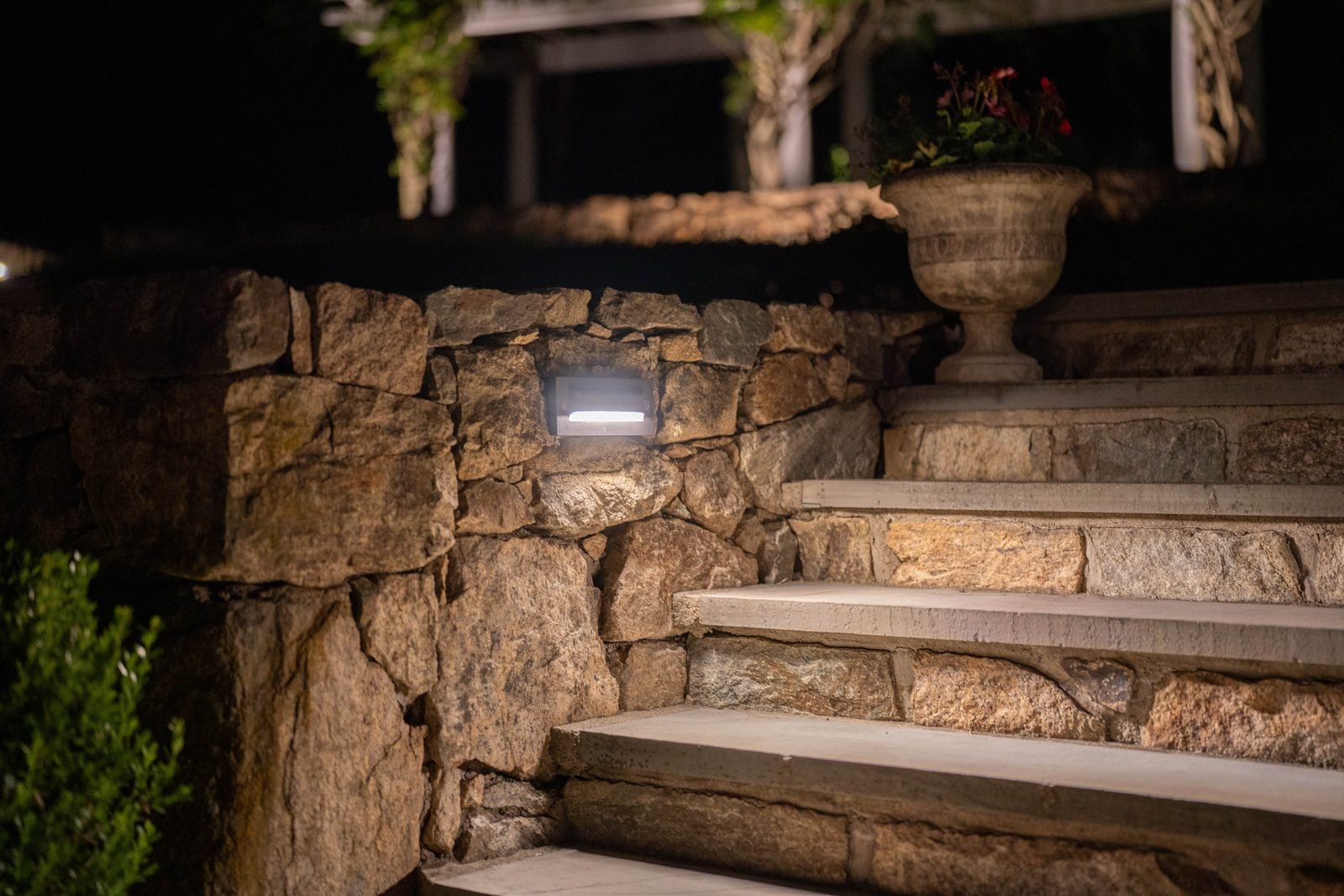 Stone steps lit tread by tread from fixtures set into the wall beside them
