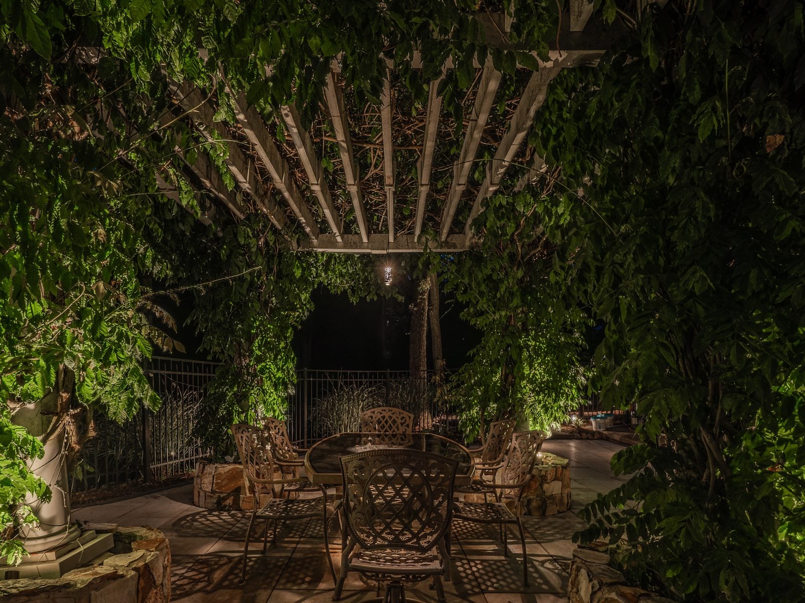 An outdoor room lit for the evening, timber structure lit from below