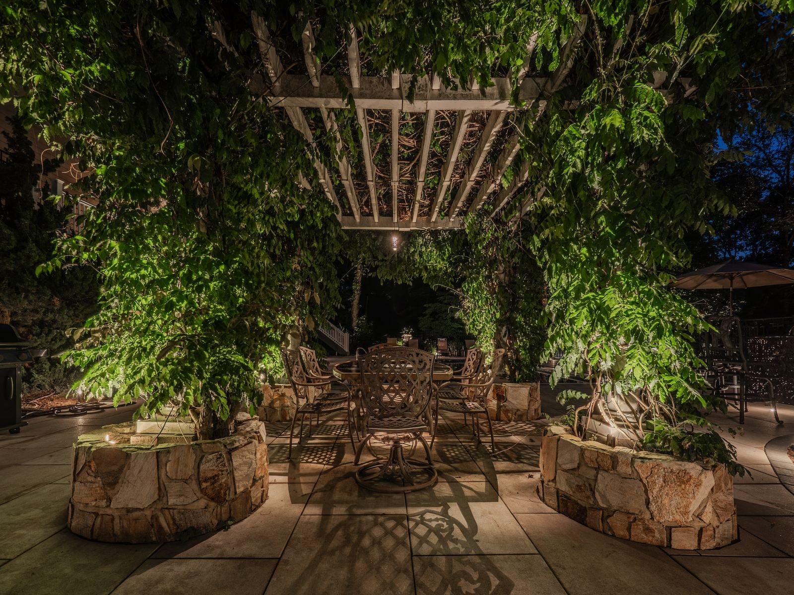 A lit patio and seating area, planting washed behind the furniture