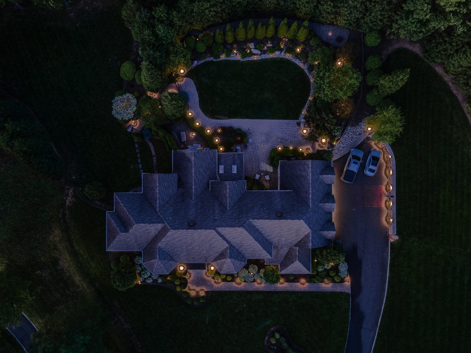 A lit estate seen from above after dark, the lighting scheme readable as one design