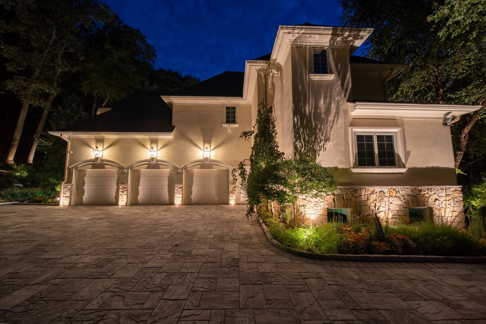 A New Jersey home at night with its facade washed in warm light from ground-set fixtures