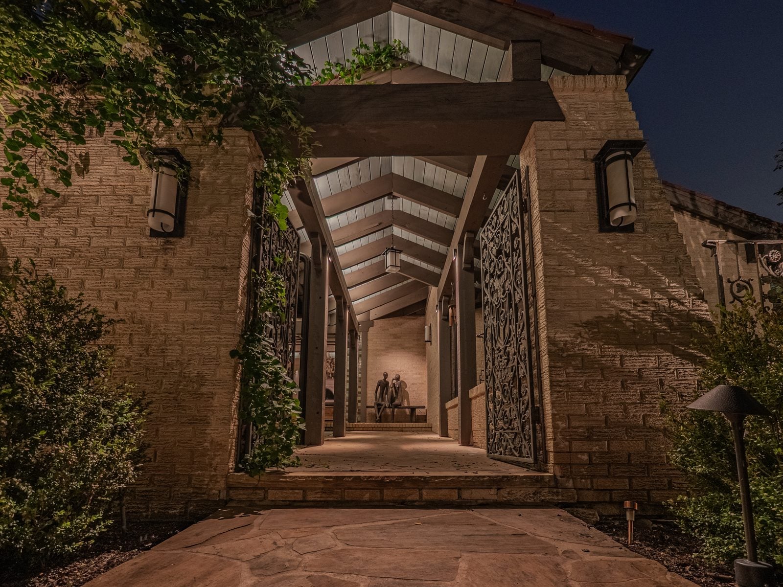 An outdoor room lit for the evening, timber structure lit from below