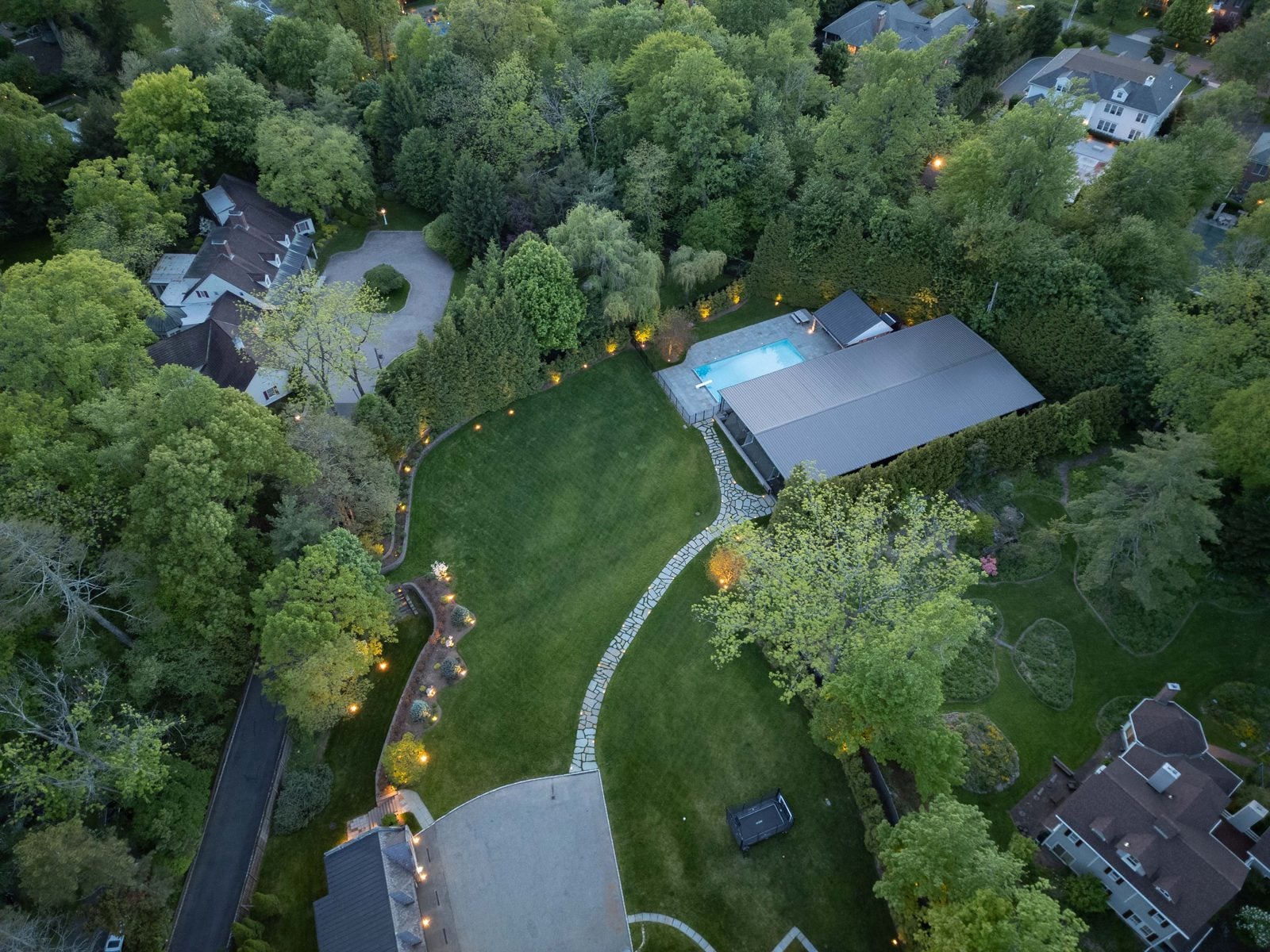 An aerial at dusk, the property's beds, walks and drive outlined in light