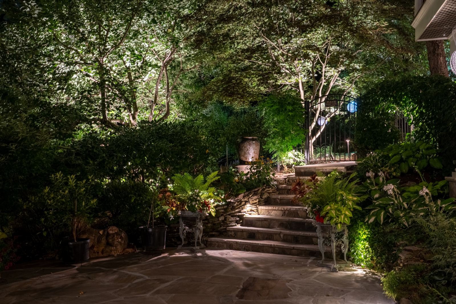 Planting beds and a walk lit after dark, path fixtures washing the foliage