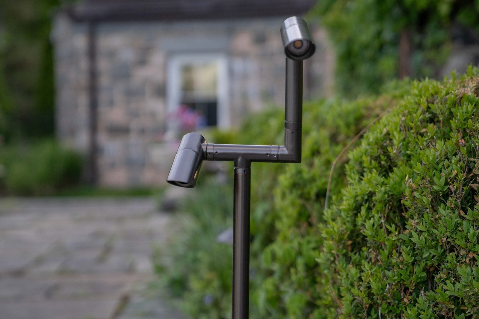 A path light beside a stone walk, washing the planting behind it