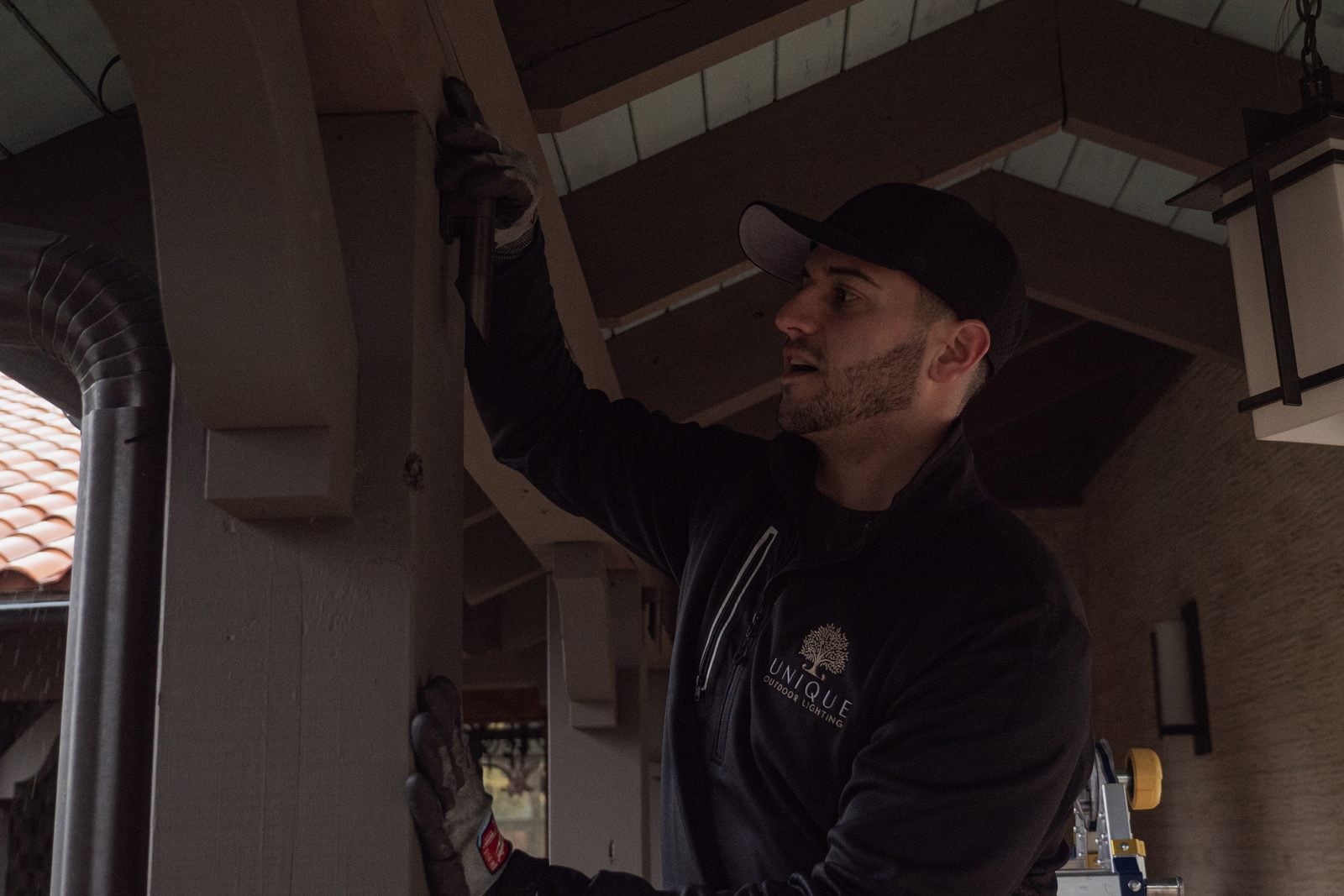 A technician aiming a fixture under a covered entry