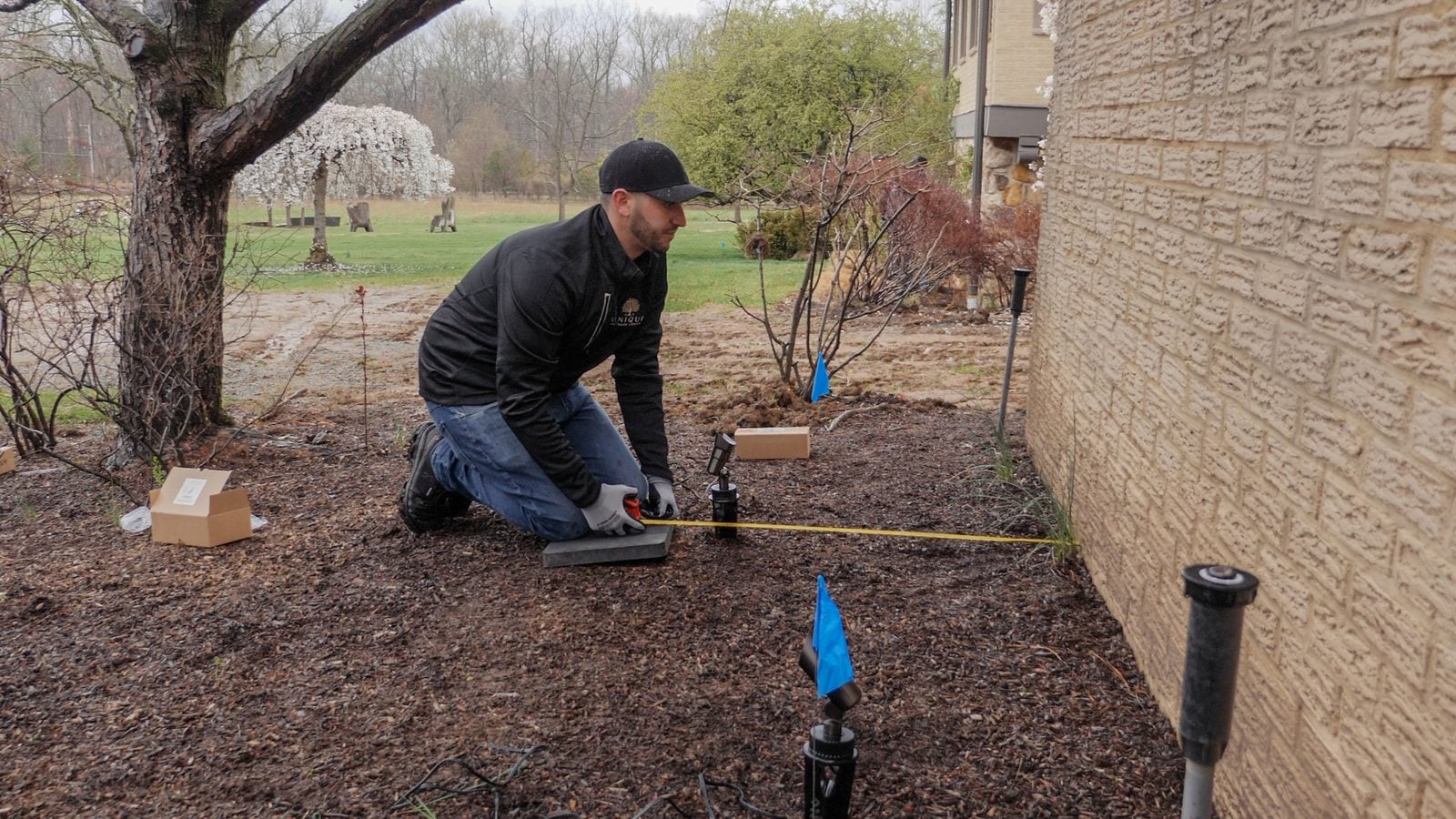 An installer kneeling to set a spotlight into a planting bed
