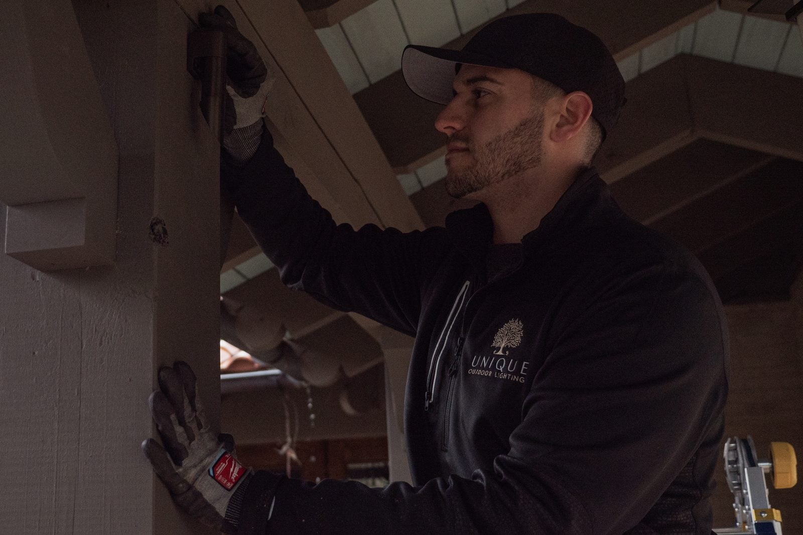 A Unique Outdoor Lighting technician fitting a fixture to a timber portico beam