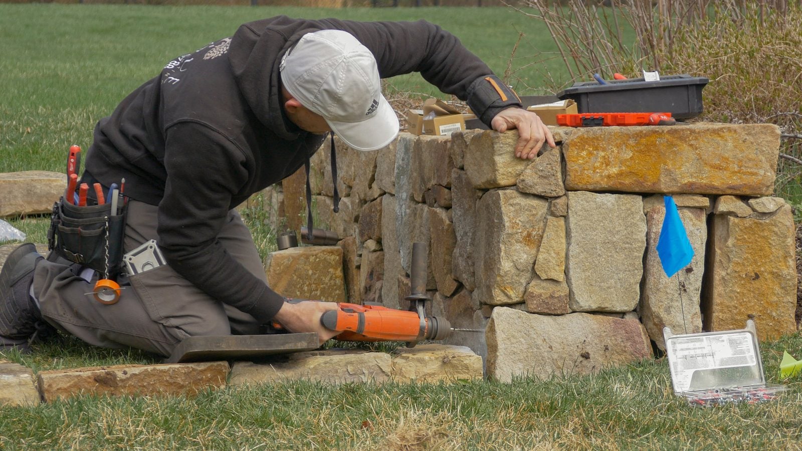 An installer drilling into a stone wall to mount a fixture